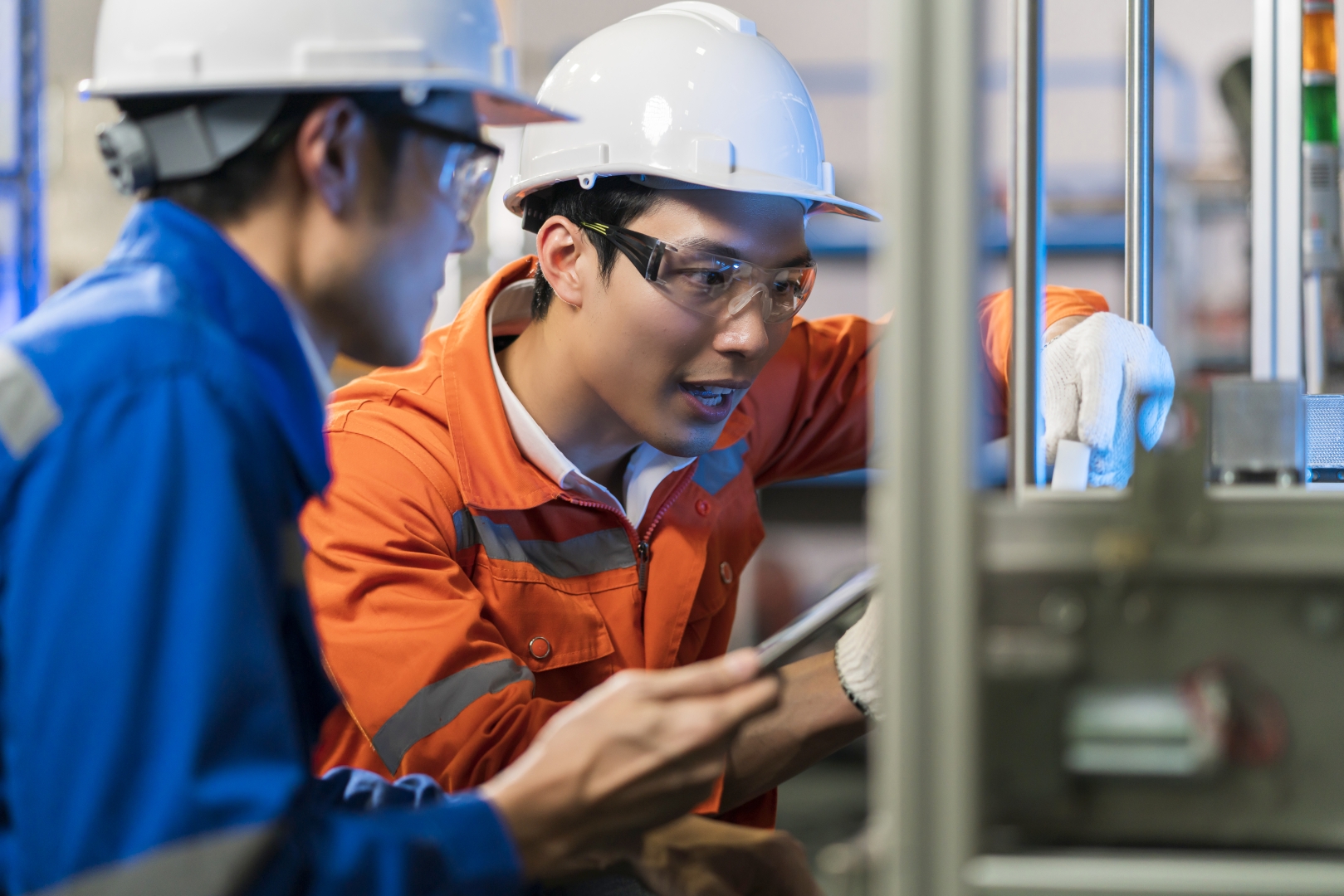 A man wearing safety equipment works with on an instrustrial machine