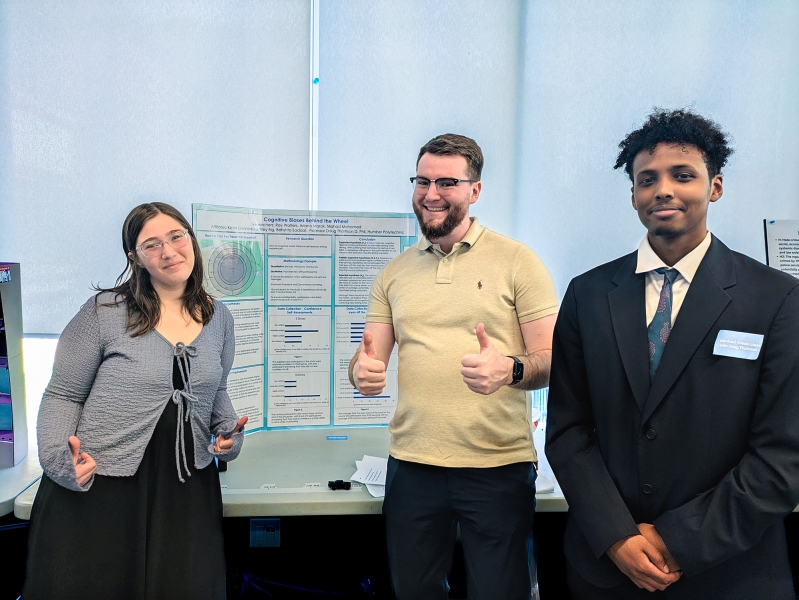 The students stand in front of their poster presentation