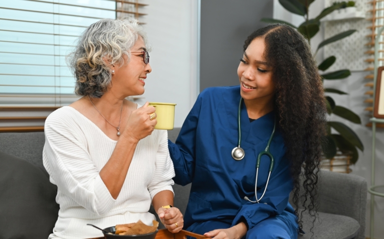 A nurse sits with a patient while they are eating.